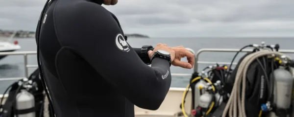 Plongeur vérifiant sa montre de plongée automatique au poignet avant mise à l'eau